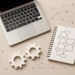 A modern desk scene with a laptop, gears, flowchart notes, and network icons representing AI automation in digital work